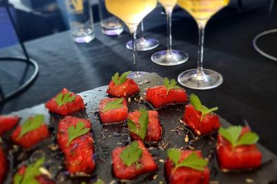 Huîtres gratinées garnies de fromage et épices, présentées sur un plateau en bois, avec légumes en arrière-plan.
