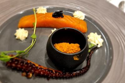 Huîtres gratinées garnies de fromage et épices, présentées sur un plateau en bois, avec légumes en arrière-plan.