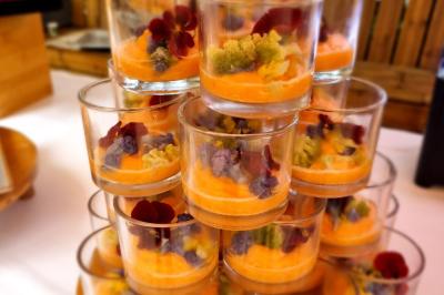 Huîtres gratinées garnies de fromage et épices, présentées sur un plateau en bois, avec légumes en arrière-plan.