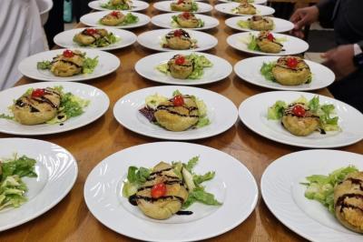 Huîtres gratinées garnies de fromage et épices, présentées sur un plateau en bois, avec légumes en arrière-plan.