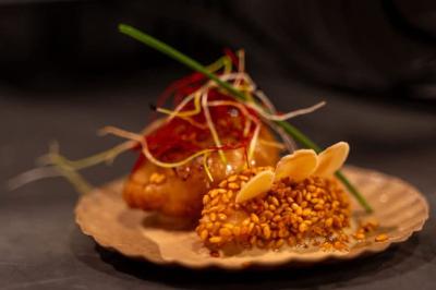 Huîtres gratinées garnies de fromage et épices, présentées sur un plateau en bois, avec légumes en arrière-plan.