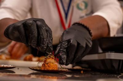Huîtres gratinées garnies de fromage et épices, présentées sur un plateau en bois, avec légumes en arrière-plan.