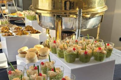 Huîtres gratinées garnies de fromage et épices, présentées sur un plateau en bois, avec légumes en arrière-plan.
