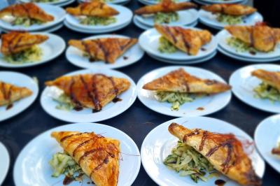 Huîtres gratinées garnies de fromage et épices, présentées sur un plateau en bois, avec légumes en arrière-plan.