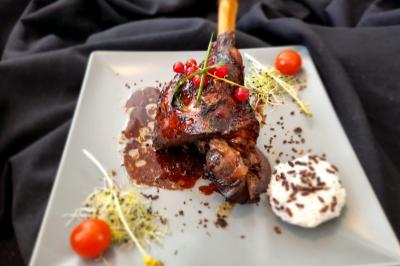 Huîtres gratinées garnies de fromage et épices, présentées sur un plateau en bois, avec légumes en arrière-plan.