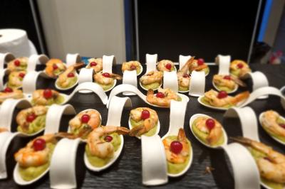 Huîtres gratinées garnies de fromage et épices, présentées sur un plateau en bois, avec légumes en arrière-plan.
