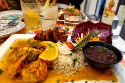 Huîtres gratinées garnies de fromage et épices, présentées sur un plateau en bois, avec légumes en arrière-plan.