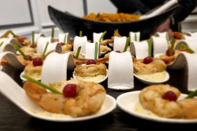 Huîtres gratinées garnies de fromage et épices, présentées sur un plateau en bois, avec légumes en arrière-plan.