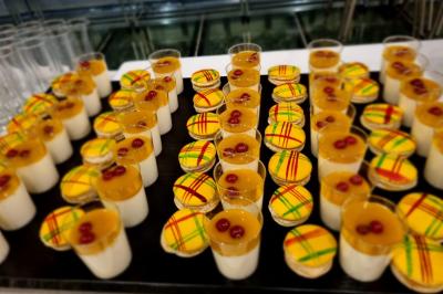 Huîtres gratinées garnies de fromage et épices, présentées sur un plateau en bois, avec légumes en arrière-plan.