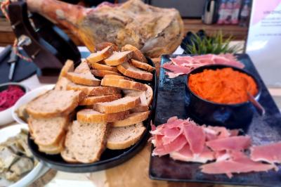 Huîtres gratinées garnies de fromage et épices, présentées sur un plateau en bois, avec légumes en arrière-plan.