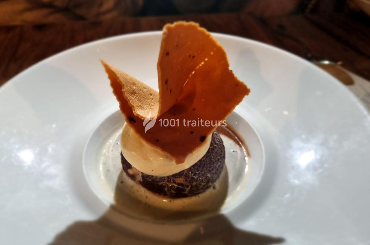 Dessert composé d'une boule de glace sur un fondant au chocolat, décoré d'une fine tuile croustillante.