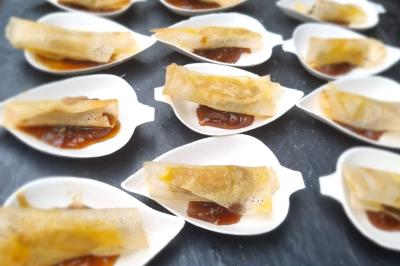 Huîtres gratinées garnies de fromage et épices, présentées sur un plateau en bois, avec légumes en arrière-plan.