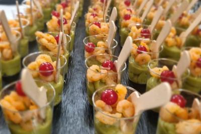 Huîtres gratinées garnies de fromage et épices, présentées sur un plateau en bois, avec légumes en arrière-plan.