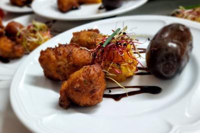 Huîtres gratinées garnies de fromage et épices, présentées sur un plateau en bois, avec légumes en arrière-plan.