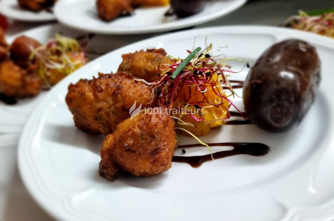 Assiette composée d'accras dorés, boudin noir, purée de légumes et pousses décoratives avec filet de sauce.