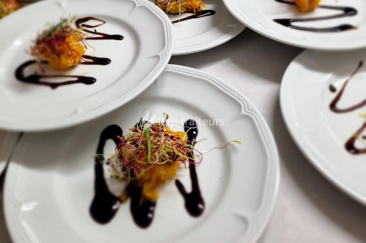 Assiette blanche contenant une préparation garnie de pousses et entourée de traits de sauce foncée.