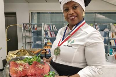 Huîtres gratinées garnies de fromage et épices, présentées sur un plateau en bois, avec légumes en arrière-plan.