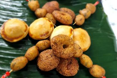 Huîtres gratinées garnies de fromage et épices, présentées sur un plateau en bois, avec légumes en arrière-plan.