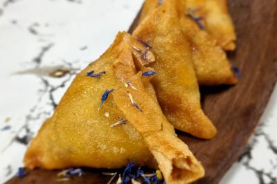 Huîtres gratinées garnies de fromage et épices, présentées sur un plateau en bois, avec légumes en arrière-plan.