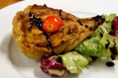 Huîtres gratinées garnies de fromage et épices, présentées sur un plateau en bois, avec légumes en arrière-plan.