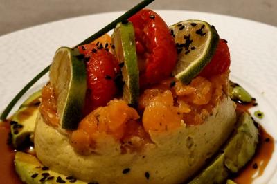 Huîtres gratinées garnies de fromage et épices, présentées sur un plateau en bois, avec légumes en arrière-plan.