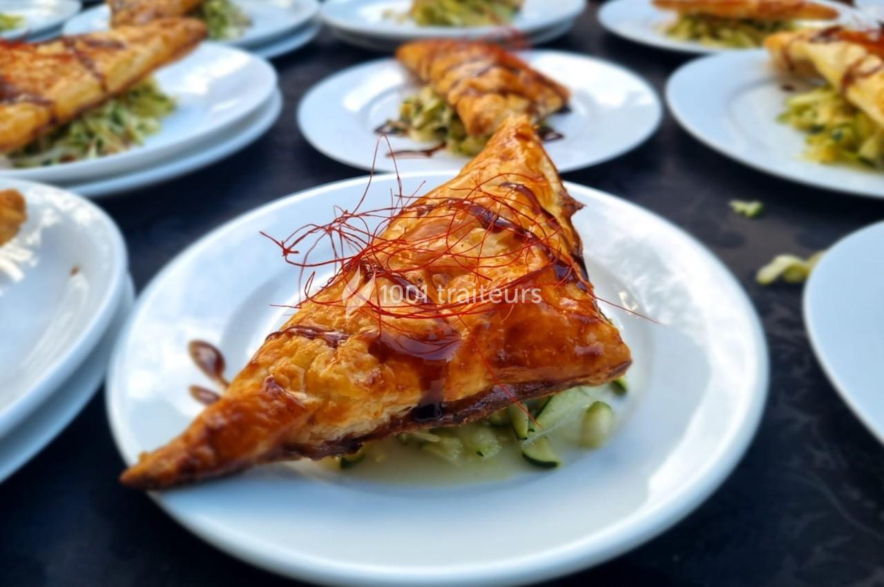 Feuilleté doré garni de légumes, servi sur une assiette blanche avec une présentation soignée.