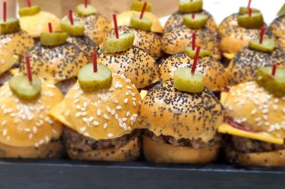 Huîtres gratinées garnies de fromage et épices, présentées sur un plateau en bois, avec légumes en arrière-plan.