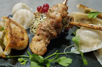 Huîtres gratinées garnies de fromage et épices, présentées sur un plateau en bois, avec légumes en arrière-plan.