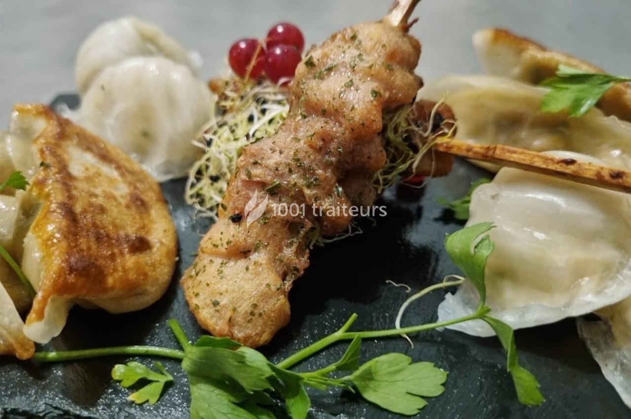 Assortiment de raviolis grillés et vapeur avec une brochette de viande, décoré de pousses et de groseilles rouges.