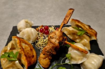 Huîtres gratinées garnies de fromage et épices, présentées sur un plateau en bois, avec légumes en arrière-plan.