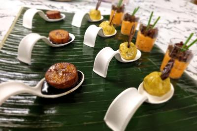 Huîtres gratinées garnies de fromage et épices, présentées sur un plateau en bois, avec légumes en arrière-plan.