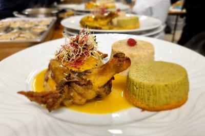 Huîtres gratinées garnies de fromage et épices, présentées sur un plateau en bois, avec légumes en arrière-plan.