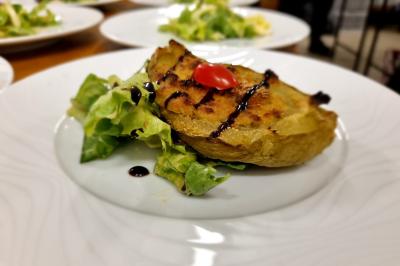Huîtres gratinées garnies de fromage et épices, présentées sur un plateau en bois, avec légumes en arrière-plan.