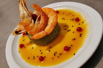 Huîtres gratinées garnies de fromage et épices, présentées sur un plateau en bois, avec légumes en arrière-plan.