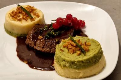 Huîtres gratinées garnies de fromage et épices, présentées sur un plateau en bois, avec légumes en arrière-plan.