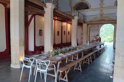 Grande table dressée avec vaisselle et décoration florale dans une salle voûtée avec tonneaux et cuves en arrière-plan.