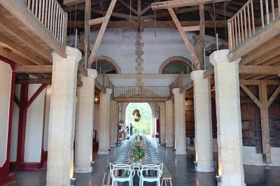 Grande table dressée avec vaisselle et décoration florale dans une salle voûtée avec tonneaux et cuves en arrière-plan.