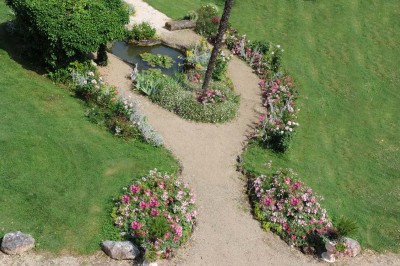 Grande table dressée avec vaisselle élégante, pains individuels et décoration florale, sous une terrasse en bois ouverte sur…