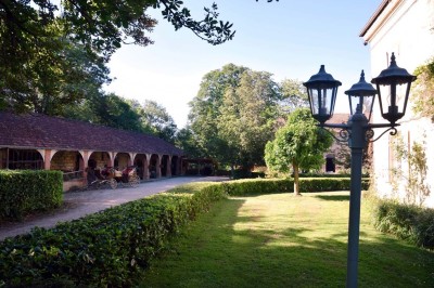 Grande table dressée avec vaisselle élégante, pains individuels et décoration florale, sous une terrasse en bois ouverte sur…