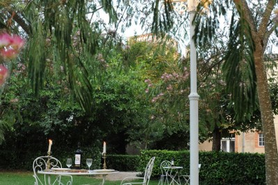 Grande table dressée avec vaisselle élégante, pains individuels et décoration florale, sous une terrasse en bois ouverte sur…