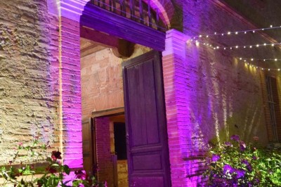 Grande table dressée avec vaisselle élégante, pains individuels et décoration florale, sous une terrasse en bois ouverte sur…