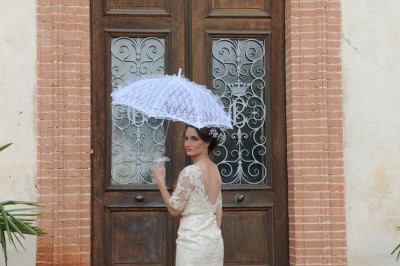 Grande table dressée avec vaisselle élégante, pains individuels et décoration florale, sous une terrasse en bois ouverte sur…