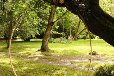 Grande table dressée avec vaisselle élégante, pains individuels et décoration florale, sous une terrasse en bois ouverte sur…