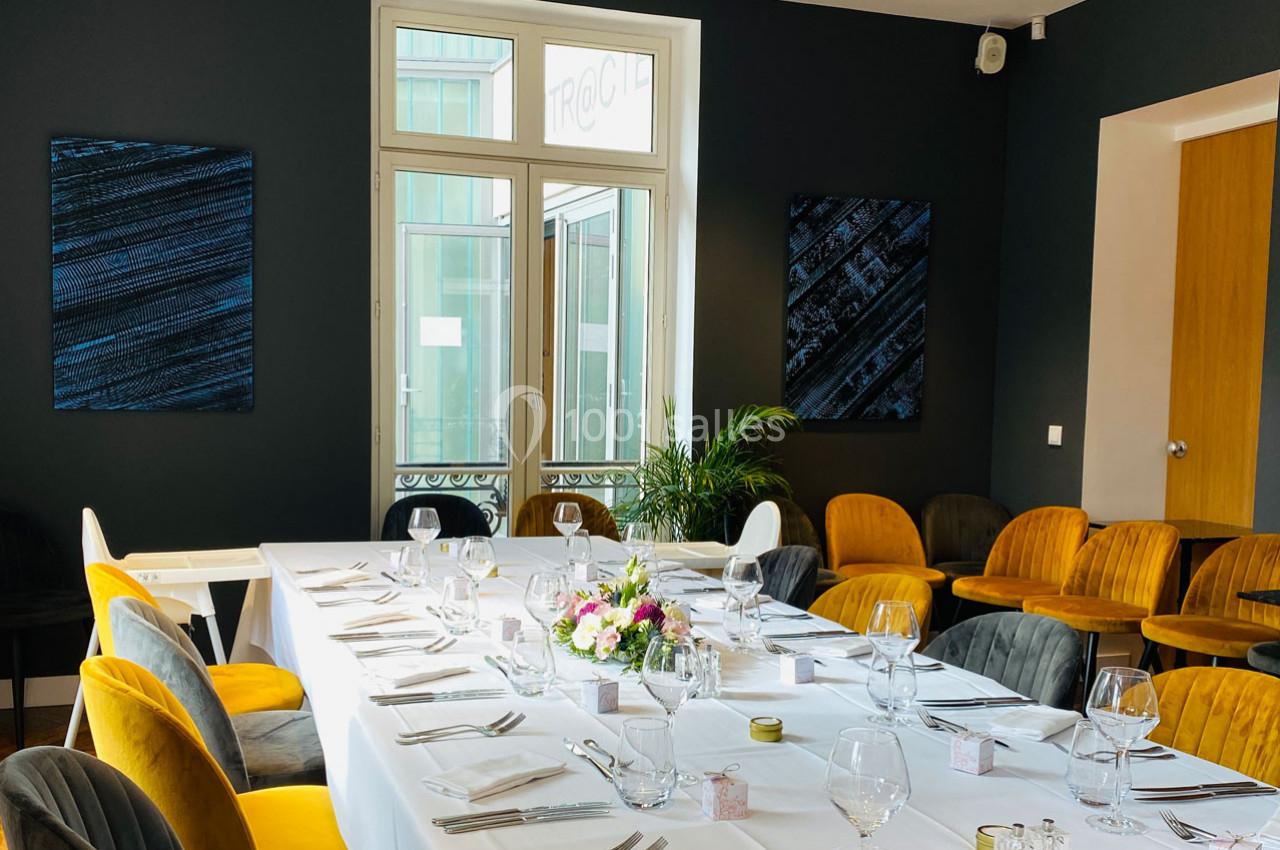 Salle de réception élégante avec une grande table dressée, des chaises colorées et des décorations modernes.