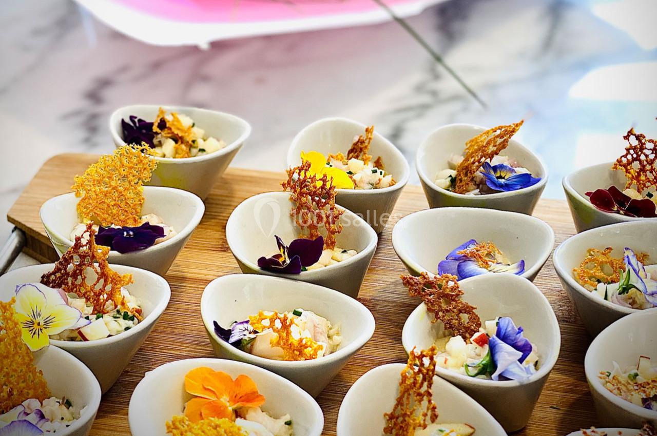 Petites verrines garnies de fleurs comestibles, de croustillants dorés et d'ingrédients frais, présentées sur un plateau en…