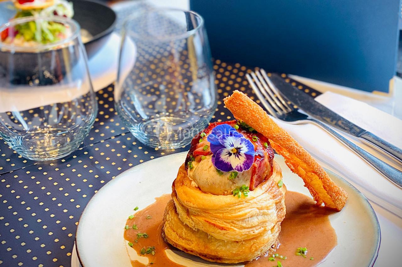 Plat gastronomique composé d'une pâte feuilletée garnie, décorée de fleurs comestibles et accompagnée d'une sauce.