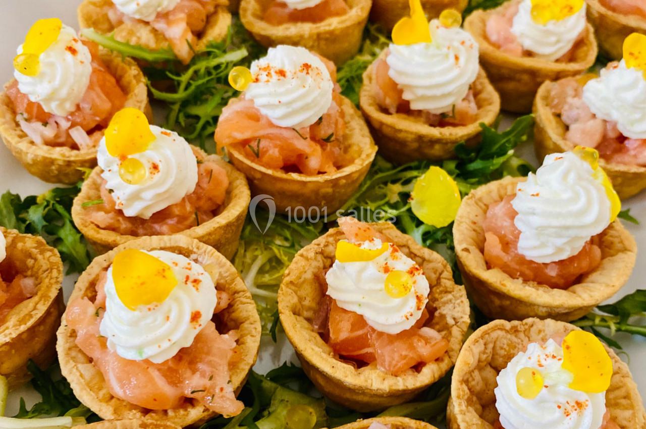 Tartelettes garnies de saumon fumé, crème fouettée et perles de citron, servies sur un lit de salade verte.
