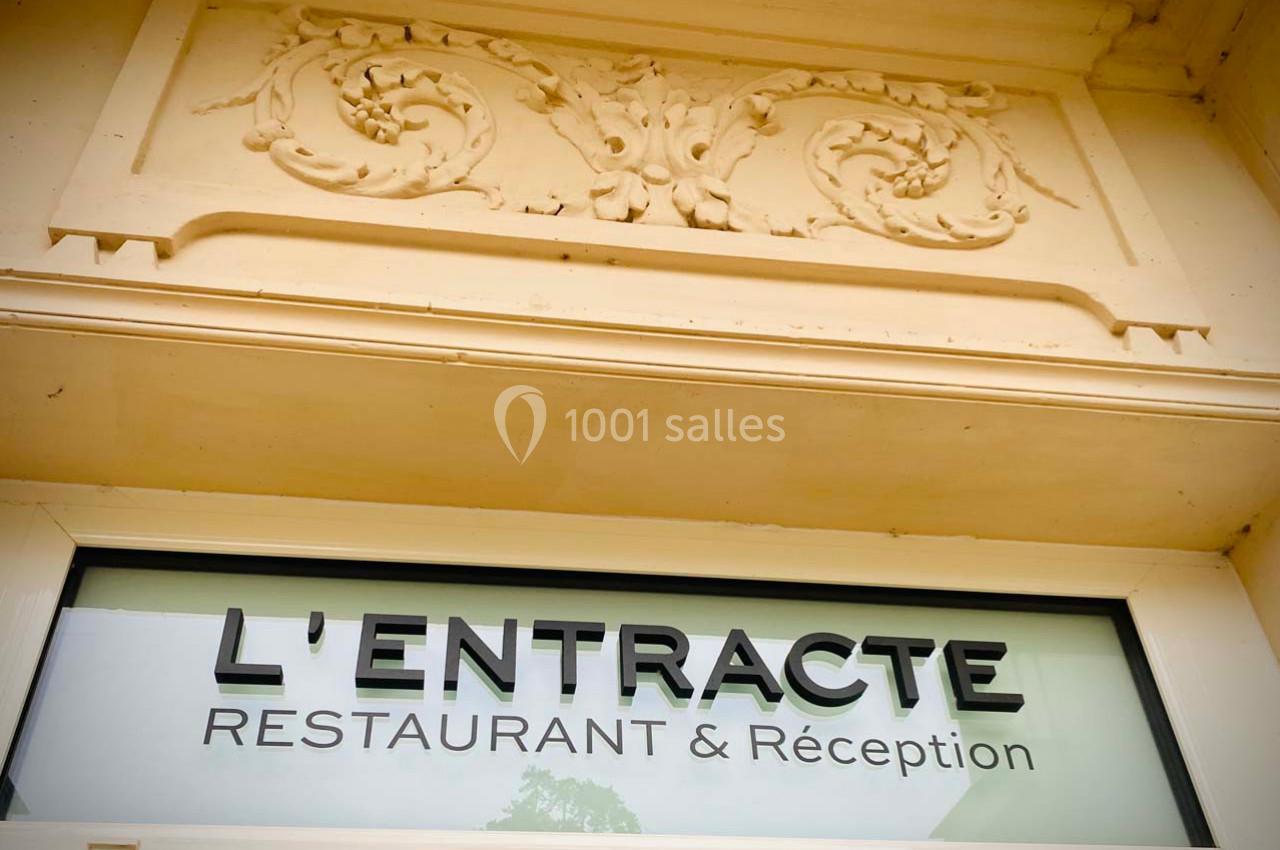 Façade d'un bâtiment avec une enseigne indiquant ’L'Entracte Restaurant & Réception’ sous une décoration sculptée.