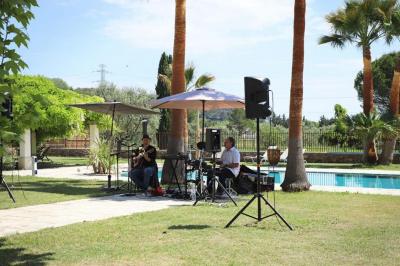 Décoration de table de mariage en extérieur avec chandeliers en verre, fleurs blanches et chaises alignées sur une pelouse.
