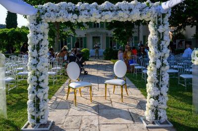 Décoration de table de mariage en extérieur avec chandeliers en verre, fleurs blanches et chaises alignées sur une pelouse.